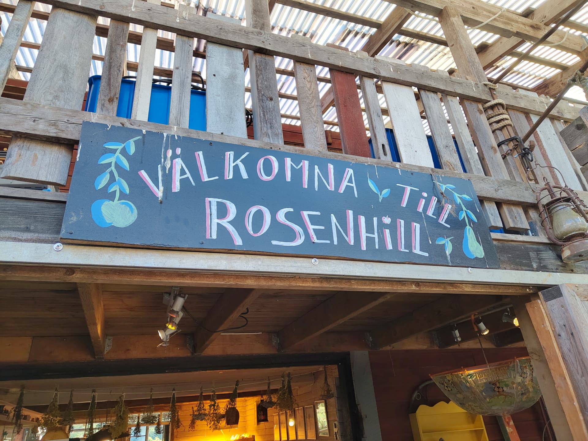 Handmålad skylt med texten Välkomna till Rosenhill i trädgårdens uthus